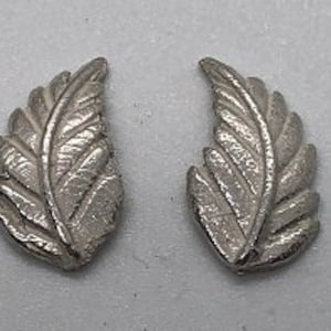 May include: A pair of silver leaf-shaped earrings. The leaves have a detailed, textured design.