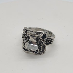 May include: A silver ring featuring a detailed design of a saddle. The ring is made of metal and has a smooth finish.