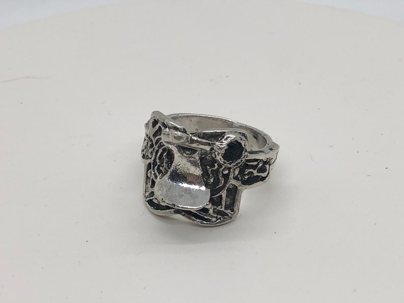 May include: A silver ring featuring a detailed design of a saddle. The ring is made of metal and has a smooth finish.