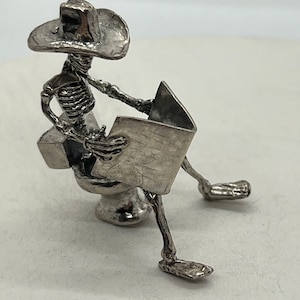 Cowboy On the Thrown Reading the Newspaper, Sterling Silver Bones Alive skeleton sculpture, hand cast by Don Norris in Tucson.