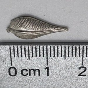 May include: A silver leaf-shaped pendant, approximately 1 cm long, with a textured surface.