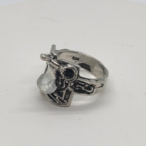 May include: A silver ring featuring a detailed saddle design. The ring is marked with the number "925" on the band.