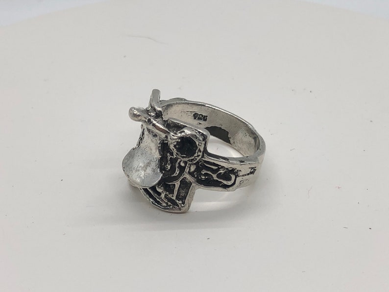 May include: A silver ring featuring a detailed saddle design. The ring is marked with the number "925" on the band.
