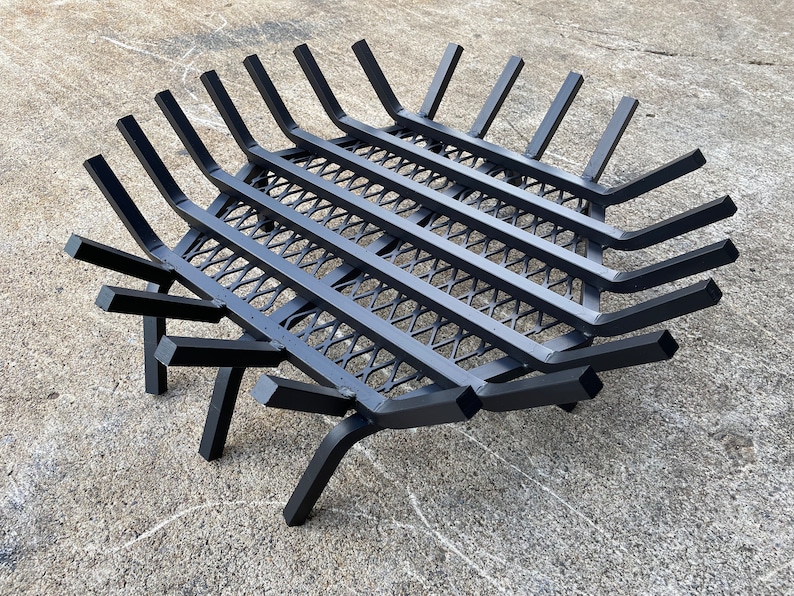 Op de afbeelding: Zwarte metalen vuurkorf met een roosterontwerp en meerdere poten. De korf is ontworpen om houtblokken voor een vuurplaats te houden.