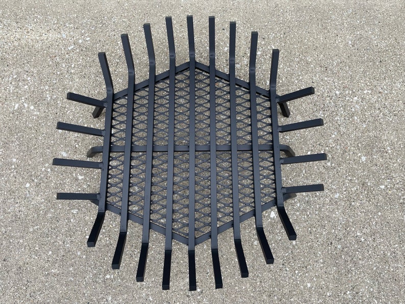 Op de afbeelding: Zwarte metalen vuurkorf met een zeshoekige vorm en een ruitvormig gaas. De vuurkorf heeft 16 spaken die vanuit het midden uitstralen.