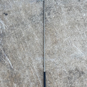 May include: A silver metal hook with a black rubber handle. The hook is about 30 inches long.