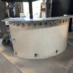 May include: A semi-circular, brushed metal component featuring a flat top flange and a row of evenly spaced circular perforations along the upper edge. The curved body includes several small, circular mounting holes positioned near the base.
