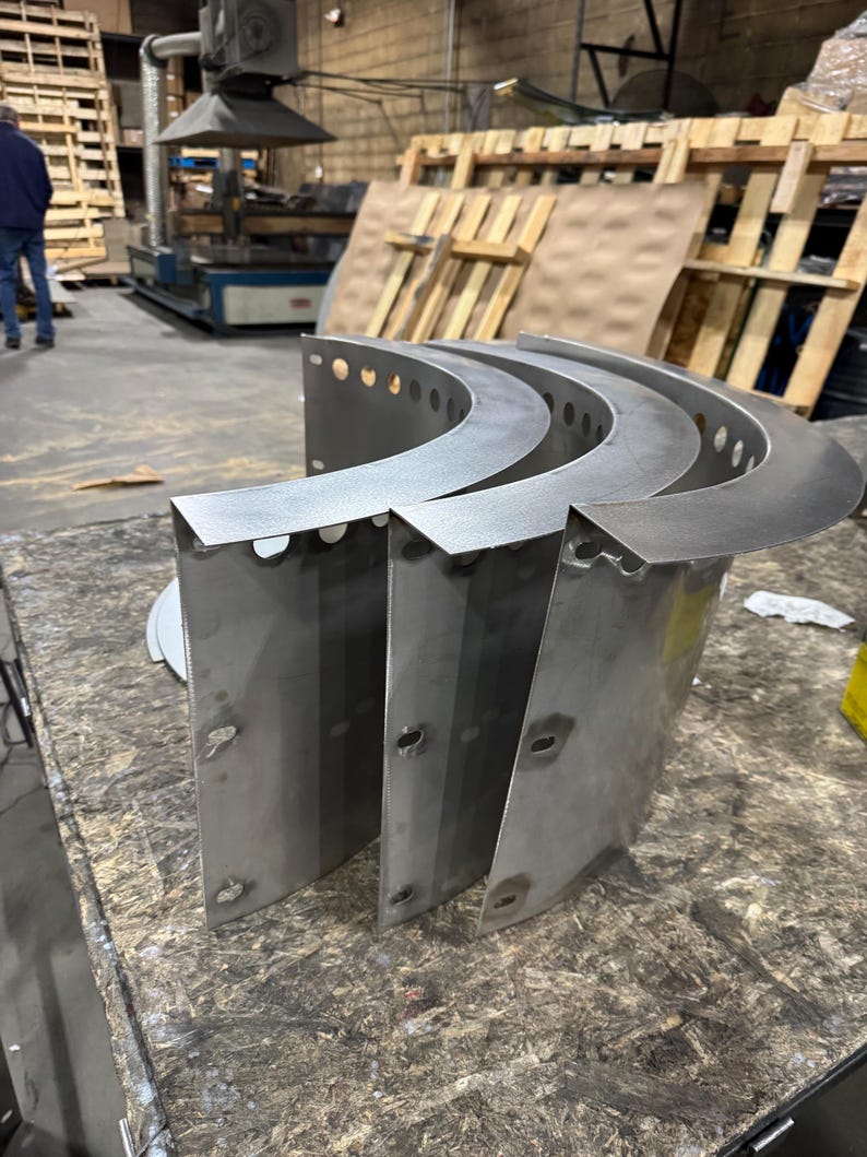 May include: Three curved, silver-colored metal panels with a smooth finish. Each panel features a wide, flat top flange with a series of evenly spaced circular holes along the edge and vertical side sections with additional punched slots.