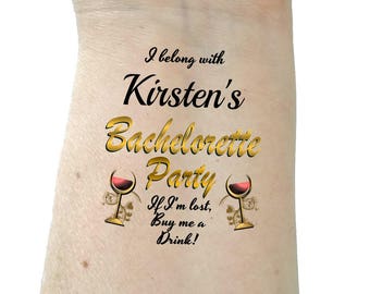 May include: A temporary tattoo with the text "I belong with Kirsten's Bachelorette Party. If I'm lost, Buy me a Drink!" and two wine glass images.