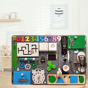 May include: A gray wooden activity board for toddlers with various textures and activities, including a zipper, a lock, a light switch, an outlet, a clock, a maze, gears, a chain, a key, a spinner, a shoe, a remote control, and a rabbit. The numbers 0-9 are displayed at the top of the board.