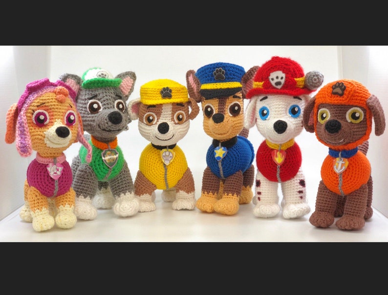 Op de afbeelding: Zeven gehaakte pluche speelgoed van de Paw Patrol-personages. De personages zijn Chase, Marshall, Skye, Rocky, Zuma, Rubble en Everest. De speelgoedjes dragen allemaal hun kenmerkende uniformen en accessoires.
