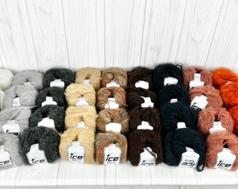 Puede incluir: Una colección de 40 ovillos de lana en varios colores, incluyendo blanco, gris, beige, marrón, negro, rosa y naranja. La lana está dispuesta en filas sobre una superficie blanca. Cada ovillo tiene una etiqueta blanca con la palabra "Ice" impresa en ella.