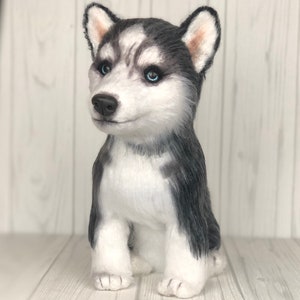 May include: A plush husky puppy toy with black and white fur, blue eyes, and a sitting pose.