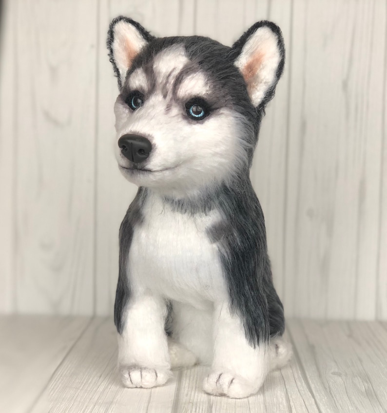 May include: A plush husky puppy toy with black and white fur, blue eyes, and a sitting pose.