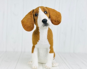 May include: A crocheted beagle dog toy with brown and white fur. The dog is sitting with its head tilted up and its ears perked.