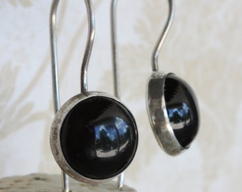 May include: A pair of silver dangle earrings with black round stones.