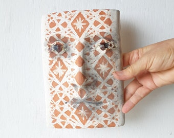 Geometric pottery wall face sculpture with inlaid crystal pattern, orange and white ceramic art tile