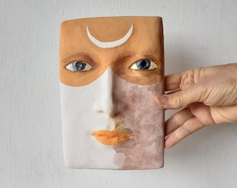 Female face art mask, ceramic wall sculpture with crescent moon tattoo on her forehead from Louise Fulton Studio, Australian made