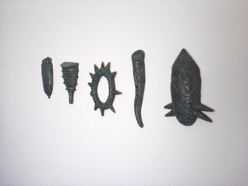 May include: Six small ceramic sculptures in various shapes, including a cone, a ring, a spike, and a long, thin shape. The sculptures are all a dark blue-green color.