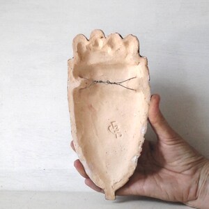 May include: A terracotta heart-shaped wall hanging with a wire hanger on the back. The back of the heart has a small, stamped mark that reads "L.K.2".