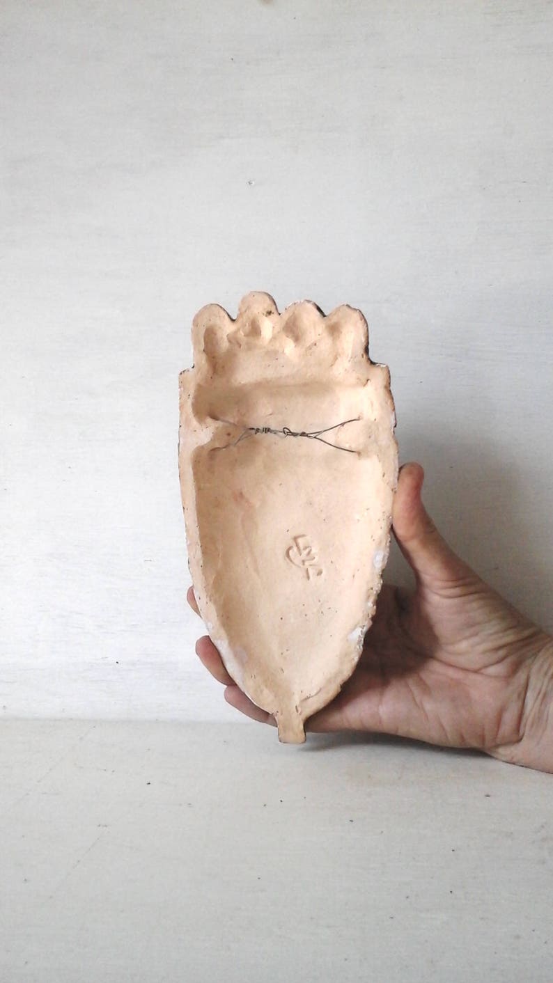 May include: A terracotta heart-shaped wall hanging with a wire hanger on the back. The back of the heart has a small, stamped mark that reads "L.K.2".