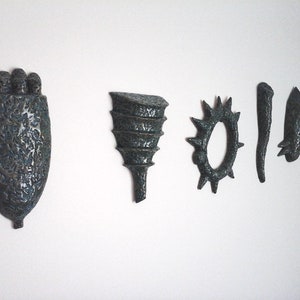 May include: Five ceramic wall sculptures in shades of blue and green. The sculptures are abstract and organic in shape, with textured surfaces.