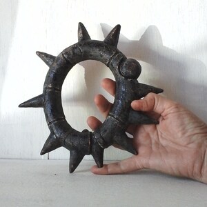 May include: A black metal ring with sharp points around the edge. The ring is about 6 inches in diameter and has a textured surface.