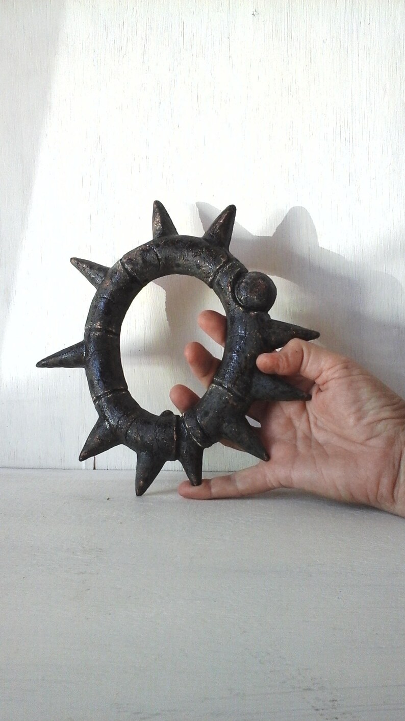 May include: A black metal ring with sharp points around the edge. The ring is about 6 inches in diameter and has a textured surface.