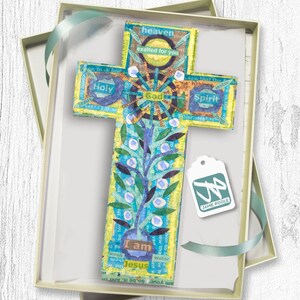 Puede incluir: Una cruz de madera colorida con un dise&ntilde;o floral azul y verde y las palabras "Yo soy Jes&uacute;s" en el centro. La cruz est&aacute; en una caja de regalo con una etiqueta que dice "Jamie Poole".