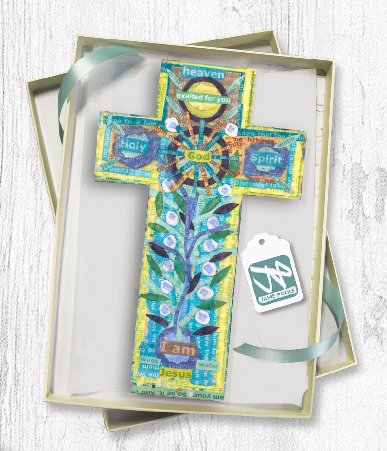 Puede incluir: Una cruz de madera colorida con un dise&ntilde;o floral azul y verde y las palabras "Yo soy Jes&uacute;s" en el centro. La cruz est&aacute; en una caja de regalo con una etiqueta que dice "Jamie Poole".