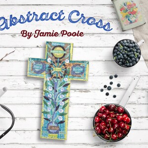Puede incluir: Una cruz abstracta azul y amarilla con las palabras "Yo soy Jes&uacute;s", "Santo", "Dios", "Esp&iacute;ritu" y "Cielo" en ella. La cruz est&aacute; sobre un fondo de madera blanca con varios cuencos de fruta y otros art&iacute;culos.