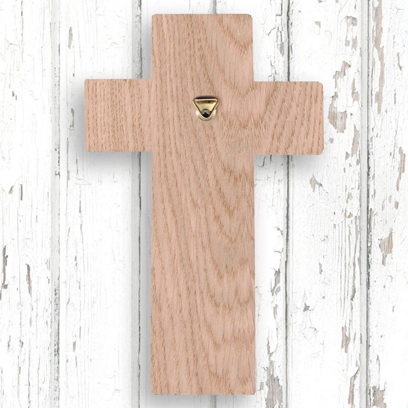 Puede incluir: Una cruz de madera con una mancha marr&oacute;n claro. La cruz tiene un gancho de metal en la parte posterior para colgar.