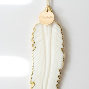 May include: White feather ornament with a gold trim and a gold tag that says "Annabelle".