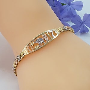 May include: A gold bracelet with a charm featuring a variety of animals, including an elephant, giraffe, and zebra. The bracelet is made of three different colors of gold, including yellow, white, and rose gold.