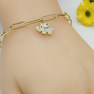 May include: A gold chain bracelet with a small, sparkly elephant charm. The elephant has a clear rhinestone for an eye.