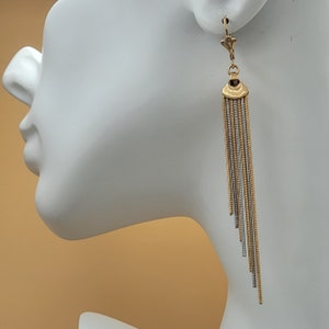 May include: Gold and silver tone dangle earrings with a chain-like design. The earrings are long and have a delicate, feminine look.