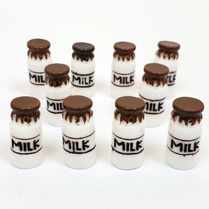 May include: Ten miniature white milk bottles with brown lids. Each bottle has the word "MILK" printed in black on the front.