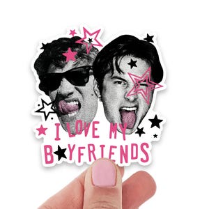 Op de afbeelding: Een gestanste sticker met twee zwart-witportretten van mensen die hun tong uitsteken, waarvan &eacute;&eacute;n met een zonnebril. Het ontwerp bevat roze en zwarte sterren en de tekst I LOVE MY BOYFRIENDS in roze letters met een zwarte ster in plaats van de O.
