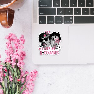 Op de afbeelding: Een gestanste sticker met zwart-witportretten van twee personen met enthousiaste uitdrukkingen, geaccentueerd door roze en zwarte sterren en de tekst "I LOVE MY BOYFRIENDS" in roze en zwarte letters, aangebracht op een zilverkleurige laptop.