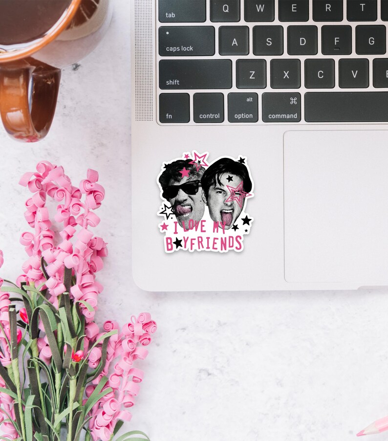 Op de afbeelding: Een gestanste sticker met zwart-witportretten van twee personen met enthousiaste uitdrukkingen, geaccentueerd door roze en zwarte sterren en de tekst "I LOVE MY BOYFRIENDS" in roze en zwarte letters, aangebracht op een zilverkleurige laptop.