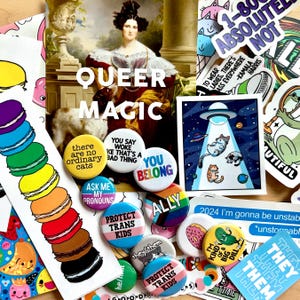 Può includere: Una collezione di bottoni e adesivi colorati con temi LGBTQ+. I bottoni presentano frasi come "Queer Magic", "You Belong", "Ask Me My Pronouns", "Protect Trans Kids" e "Ally". Gli adesivi presentano frasi come "There are no ordinary cats", "I'm gonna be unstable", "They/Them" e "Time to love them".