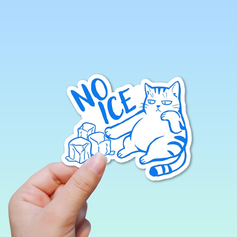 May include: A white sticker with a blue outline featuring a cartoon cat and the words "NO ICE". The cat is sitting with a grumpy expression next to several ice cubes. The sticker is held by a hand.