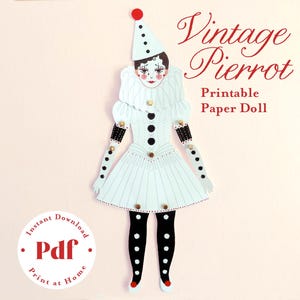 Puede incluir: Una muñeca de papel imprimible al estilo de un payaso Pierrot vintage. La muñeca es blanca con detalles en negro, incluyendo lunares en los brazos y las piernas. El texto "Vintage Pierrot Printable Paper Doll" está en escritura roja.