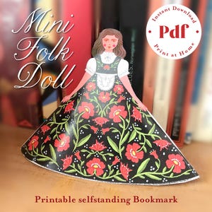 Puede incluir: Un marcapáginas de papel Mini Folk Doll con un vestido negro adornado con flores rojas y enredaderas verdes. La muñeca tiene una blusa blanca y una cara roja. La imagen incluye el texto "Mini Folk Doll" y "Printable selfstanding Bookmark".