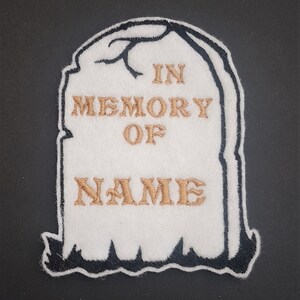 May include: White felt tombstone with black outline, embroidered with the text "In Memory Of NAME".