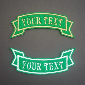 May include: Two green embroidered patches with white and gold stitching. The patches are shaped like banners and have the text "YOUR TEXT" on them.