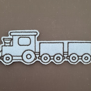 May include: A light blue felt applique of a train with a black outline. The train has a locomotive and two boxcars. The locomotive has a large window and a small chimney. The boxcars have no windows.