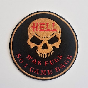 May include: A black and gold embroidered patch with a skull and the text "Hell Was Full So I Came Back".