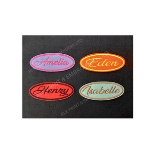 May include: Four embroidered name patches in oval shapes. The names are Amelia, Eden, Henry, and Isabelle. Each patch has a different colour scheme: pink and purple, orange and yellow, red and black, and light blue and beige. The patches are on a dark background.