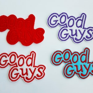 May include: Four embroidered patches with the words "Good Guys" in a playful font. The patches are in red, purple, red and white, and blue and red. The patches are likely for clothing or accessories.